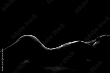 Silhouette of attractive young woman in underwear lying on dark background