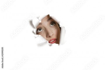 Young Middle eastern woman looking up from ripped paper hole