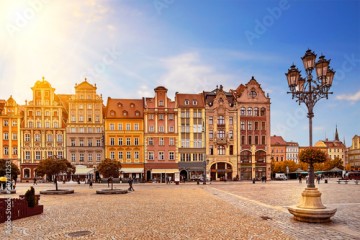 Central market square in Wroclaw Poland with old colourful houses, street lantern lamp and walking tourists people at gorgeous stunning morning sunrise sunshine. Travel vacation concept