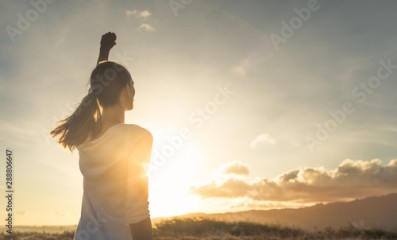 Young female outdoors with fist in the air feeling strong and confident. Victory and success concept. 