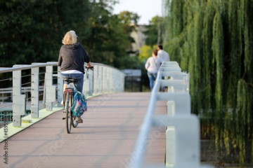 Kobieta jedzie na rowerze po moście we Wrocławiu.