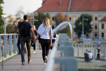 Para młodych ludzie, kobieta i mężczyzna spaceruje po moście we Wrocławiu. 