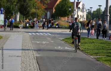 Młodzy mężczyzna jedzie na rowerze po ścieżce rowerowej we Wrocławiu.