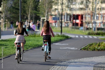 Dwie piękne kobiety jadą rowerami ścieżką rowerową w mieście, Wrocław.