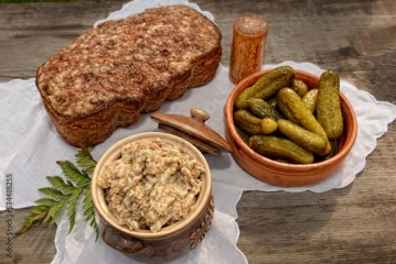 Wiejski stół — bochenek chleba, ogórki kiszone i smalec domowej roboty