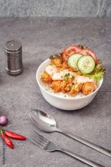 Miska z ryżem, kurczakiem w panierce oraz warzywami na stole