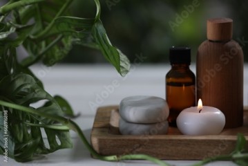 Beautiful composition with different spa products and green leaves on white table, closeup