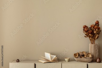 Minimalist composition of living room interior with copy space, simple beige sideboard, vase with dried flowers, books and personal accessories. Home decor. Template.