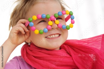 Portrait of cute little girl wearing funny glasses, smarties