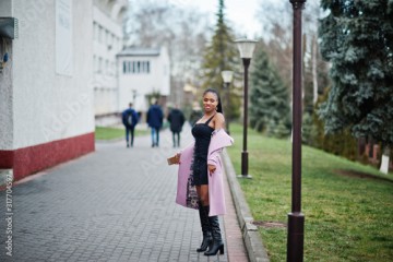 Young stylish beautiful african american woman in street, wearing fashion outfit coat.