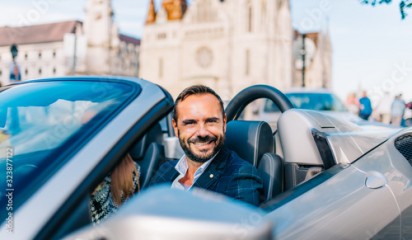 Successful happy businessman sitting in convertible super car