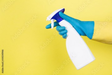 A hand with cleaning gloves squeezing a spray bottle