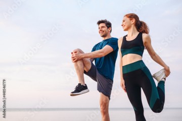 Lower couple young two friend strong sporty sportswoman sportsman woman man in sport clothes warm up training do stretch exercise on sand sea ocean beach outdoor jog on seaside in summer day morning.