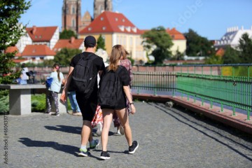 Para młodych ludzie, kobieta i mężczyzna spaceruje deptakiem, chodnikiem we Wrocławiu.