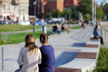 Dwie kobiety siedzą na ławkach nad rzeką Odrą we Wrocławiu. 