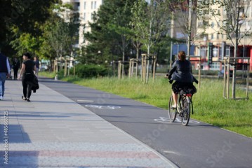 Młoda kobieta jedzie na rowerze po ścieżce rowerowej we Wrocławiu. 