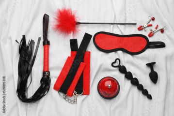Sex toys and accessories on white fabric, flat lay