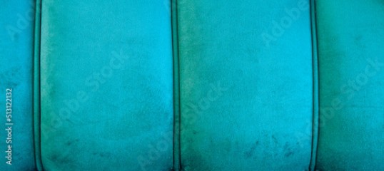 Turkusowe aksamitne tło. Zdjęcie panoramiczne turkusowego obicia, widoczne przeszycia, miękki i puchaty materiał, miejsce na tekst.