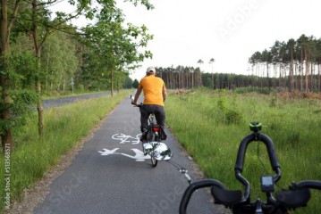 Kierownica roweru, rowerzysta na ścieżce rowerowej w lesie.