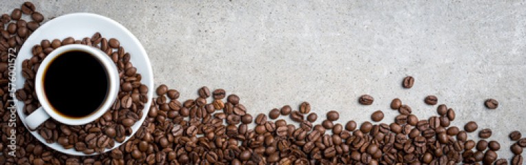 Cup of coffee with coffee beans on gray stone background. Top view