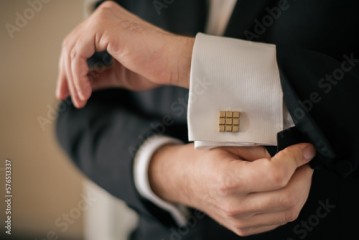 closeup of groom's hands and arms as he adjusts sleeve and cufflink