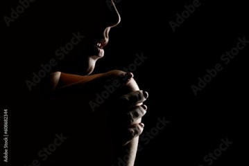 Silhouette of a unknown woman touching her shoulder o na black background