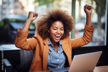 Cheerful Afro American businesswoman celebrating success while using laptop in cafe Generative AI