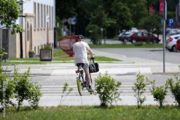 Starszy mężczyzna jedzie rowerem przez przejście dla pieszych.