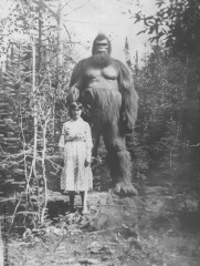 Old vintage aged mystery photograph of a lady standing with a giant bigfoot cryptid sasquatch creature in the forest