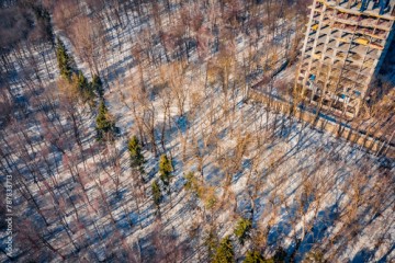 Construction of a high-rise building in early spring. Unfinished construction in the middle of the forest. Aerial morning view of Ternopil cityscape and Zahrebellya city park, Ukraine, Europe.